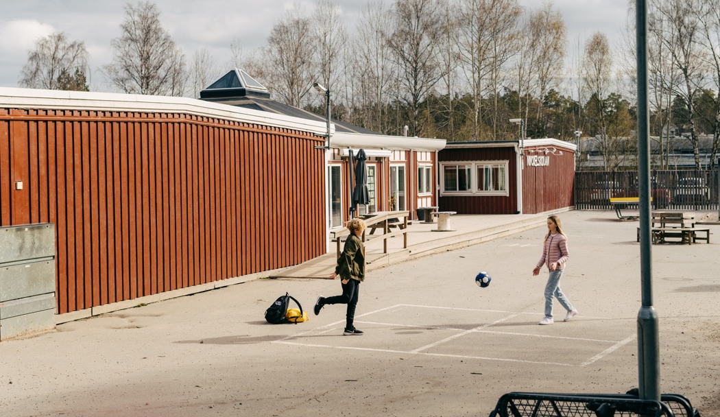 Två barn sparkar boll på en skolgård